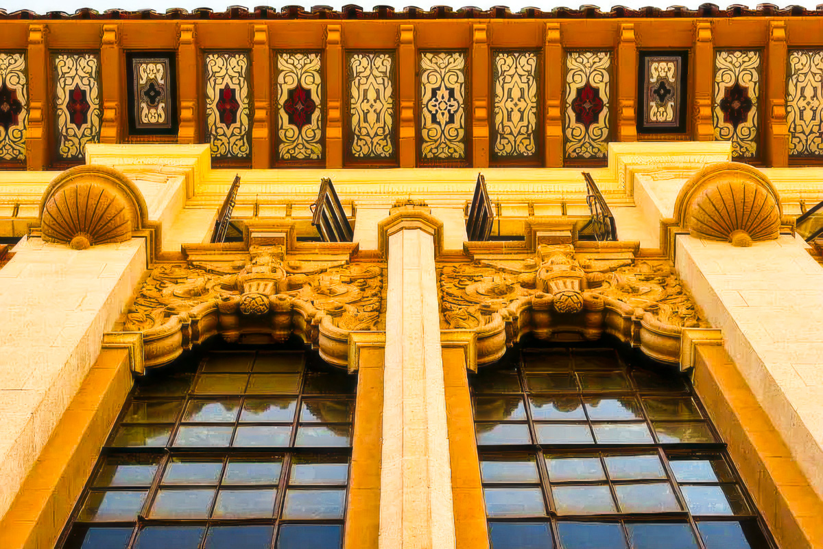 Historic red brick building facade with ornamental ironwork balcony in warm golden light